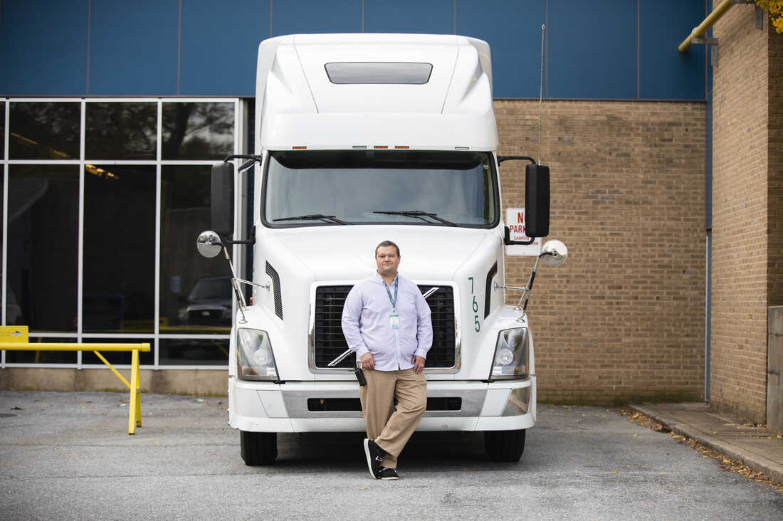 Eric Young, CDL teacher, poses for a portrait with a semi truck outside his classroom at Williamsport High School in Hagerstown, Md. on Monday, Oct. 17, 2022. The class teaches high school students how to become professional truck drivers after graduating. (Amanda Berg for NPR)